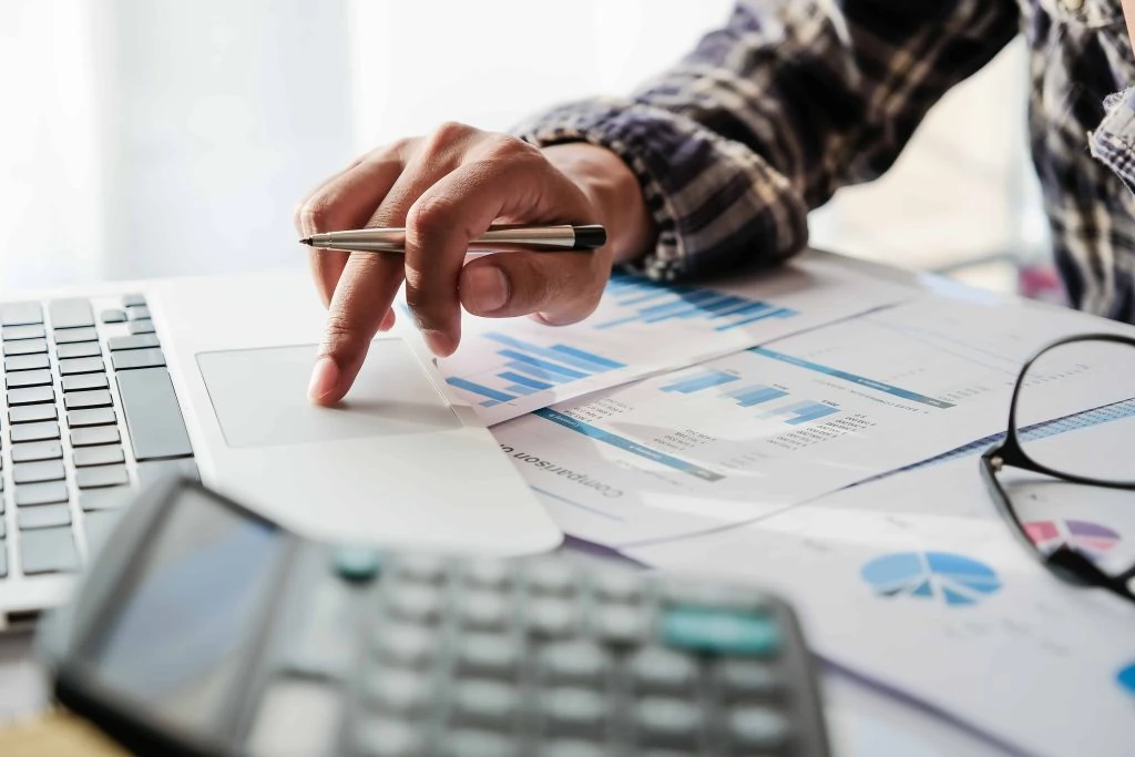 Accountant reviewing financial charts beside a laptop and calculator
