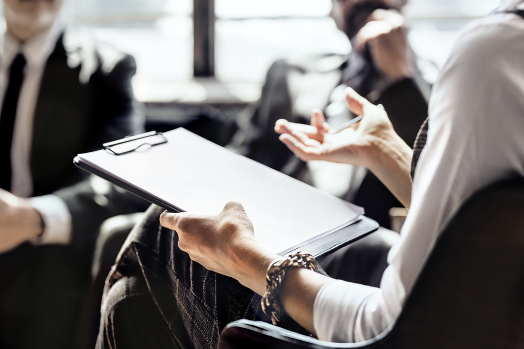 A woman holding a clipboard providing business consulting services to a group of people in Ottawa.
