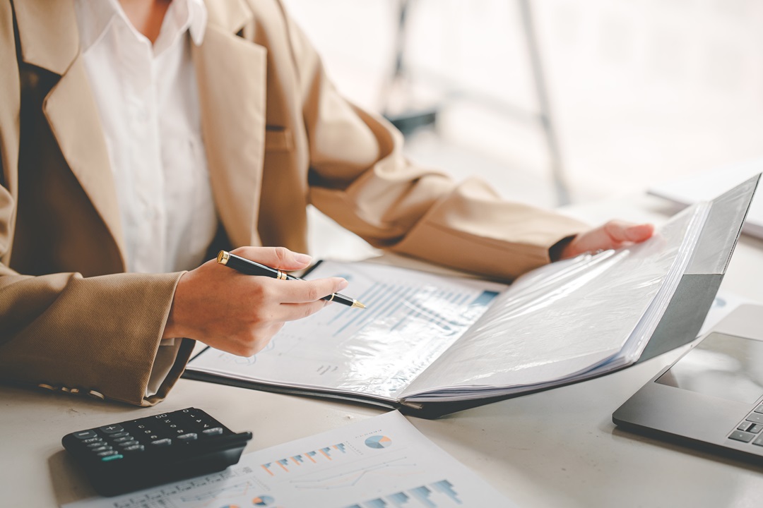 A woman is working on accounting services at a desk.