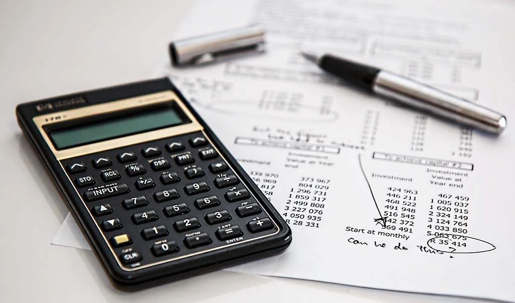 A calculator, pen, and sheet of paper with financial calculations and notes sit neatly on the desk of a Chartered Accountant in Ottawa.