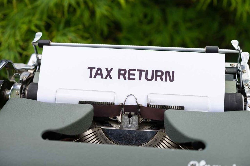 A typewriter with paper displaying the text "TAX RETURN" hints at the meticulous work of an accountant.
