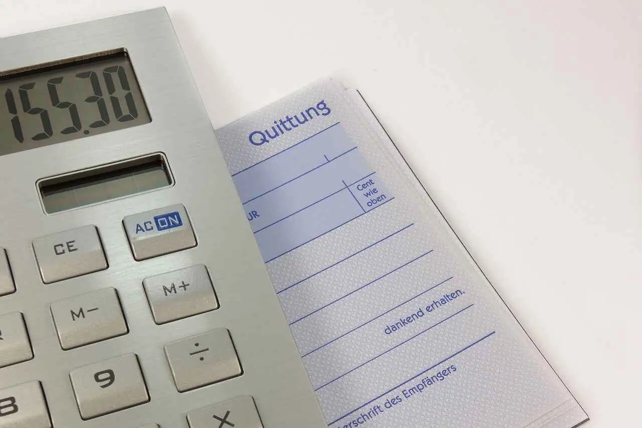 A silver calculator displaying 153.00 is partially covering a receipt pad with German text and blank fields for details, essential tools for any diligent accountant preparing a tax return.